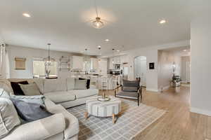 Living area with light wood-style flooring, baseboards, arched walkways, and recessed lighting