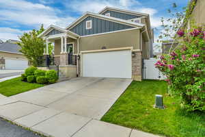 Craftsman inspired home featuring board and batten siding, stucco siding, concrete driveway, a front yard, and a gate