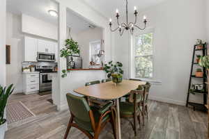 Dining room featuring light wood finished floors, a notable chandelier, and baseboards