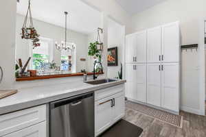 Kitchen featuring white cabinetry, an inviting chandelier, a sink, and dishwasher