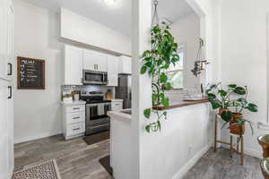 Kitchen with white cabinetry, light countertops, appliances with stainless steel finishes, and wood finished floors