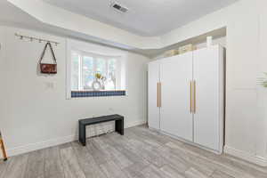 Unfurnished bedroom featuring light wood-style floors, visible vents, baseboards, and a textured ceiling