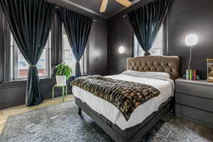 Bedroom with a ceiling fan, ornamental molding, and wood finished floors