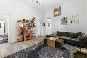 Living area with baseboards, ornamental molding, a chandelier, a towering ceiling, and wood finished floors