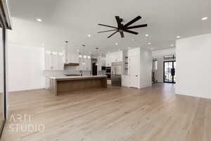 Kitchen featuring stainless steel appliances, open floor plan, light countertops, ceiling fan, and light wood-style floors