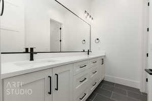 Bathroom featuring baseboards, double vanity, and tile patterned floors