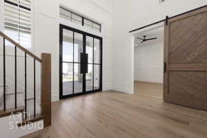 Entryway featuring wood finished floors, a ceiling fan, baseboards, and a barn door