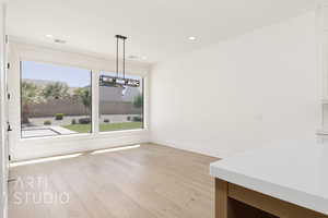 Unfurnished dining area with a chandelier, light wood-type flooring, baseboards, and recessed lighting