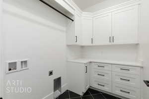Laundry room with cabinet space, electric dryer hookup, dark tile patterned floors, and washer hookup