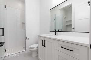Full bathroom with toilet, a stall shower, vanity, and tile patterned flooring