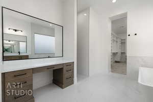 Bathroom with marble tiled floors, a freestanding bath, vanity, a walk in closet, and recessed lighting