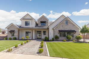View of front facade featuring a standing seam roof, a front yard, board and batten siding, and stone siding
