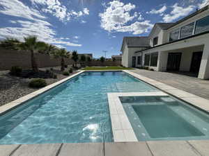 View of swimming pool featuring a fenced backyard, a patio area, and a pool with connected hot tub