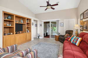 Living area with ceiling fan, vaulted ceiling, light tile patterned floors, and baseboards