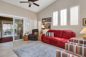 Living area with tile patterned flooring, high vaulted ceiling, a ceiling fan, and plenty of natural light