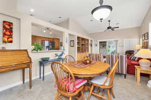 Dining space featuring vaulted ceiling, ceiling fan, light tile patterned flooring, and counter seating