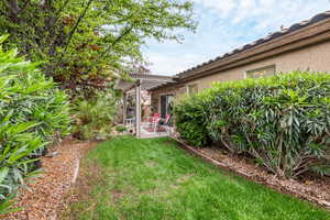 View of grassy yard featuring a pergola and a patio