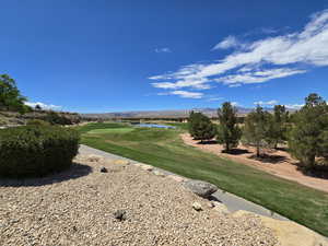 View of community with golf course view, a water and mountain view, and a yard