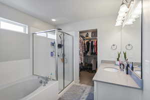 Full bath with a shower stall, vanity, a garden tub, a walk in closet, and recessed lighting