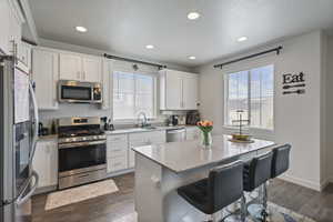Kitchen with stainless steel appliances, a sink, healthy amount of natural light, a kitchen bar, and recessed lighting