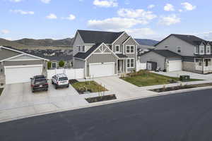 View of front facade featuring board and batten siding, a residential view, fence, a mountain view, and driveway