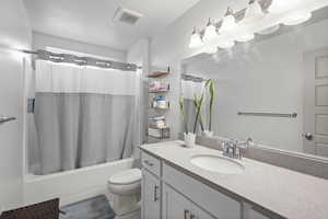 Full bathroom with shower / tub combo with curtain, toilet, and vanity