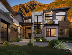 View of front of house with a mountain view, stone siding, and a front lawn