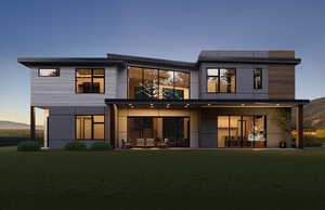 Back of property featuring a balcony and a lawn