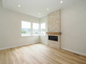 Unfurnished living room with recessed lighting, light wood finished floors, a fireplace, and baseboards