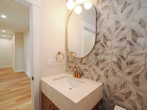 Bathroom with recessed lighting, wood finished floors, vanity, and baseboards