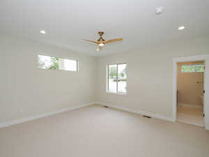 Spare room featuring healthy amount of natural light, light carpet, recessed lighting, a ceiling fan, and baseboards