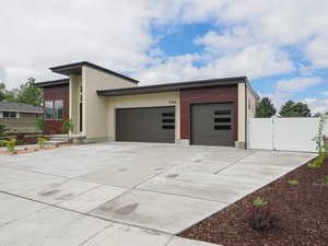View of front facade with a garage, a gate, driveway, and fence