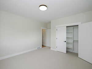 Unfurnished bedroom featuring light carpet, baseboards, and a closet