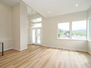 Spare room featuring a chandelier, light wood-style flooring, baseboards, and recessed lighting