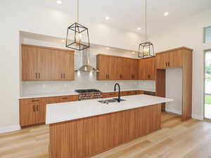 Kitchen featuring wall chimney exhaust hood, a sink, tasteful backsplash, light countertops, and recessed lighting