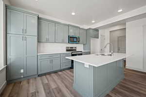 Kitchen featuring appliances with stainless steel finishes, a sink, dark wood-style flooring, recessed lighting, and light countertops