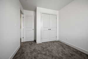 Unfurnished bedroom featuring carpet floors, baseboards, and a closet