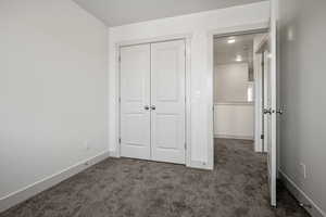 Unfurnished bedroom featuring carpet flooring, a closet, and baseboards