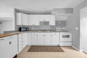 ADU - Kitchen with white appliances, a sink, light floors, white cabinetry, and recessed lighting