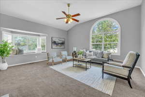 Living room with a ceiling fan, carpet, lofted ceiling, and baseboards