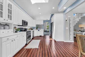 Kitchen featuring appliances with stainless steel finishes, glass insert cabinets, light countertops, white cabinetry, and recessed lighting
