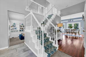 Stairway featuring a chandelier, a towering ceiling, baseboards, and carpet floors