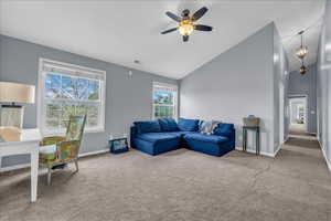 Carpeted loft area featuring a ceiling fan, baseboards, and high vaulted ceiling