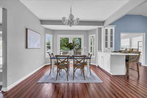 Dining room with a chandelier, baseboards, and dark wood-style floors