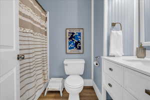 Full bath featuring wood finished floors, toilet, vanity, and a shower with curtain