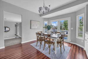 Dining room featuring a chandelier, baseboards, healthy amount of natural light, and dark wood-style floors