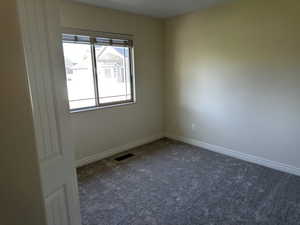 Empty room featuring dark carpet and baseboards