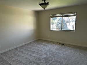 Empty room with carpet flooring, baseboards, and a textured ceiling