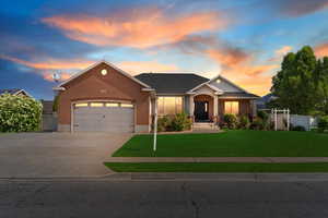 View of front of home featuring brick siding, a garage, driveway, and a gate
