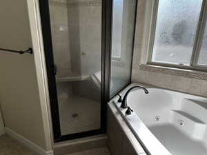 Bathroom featuring a shower stall, a whirlpool tub, tile patterned flooring, and baseboards